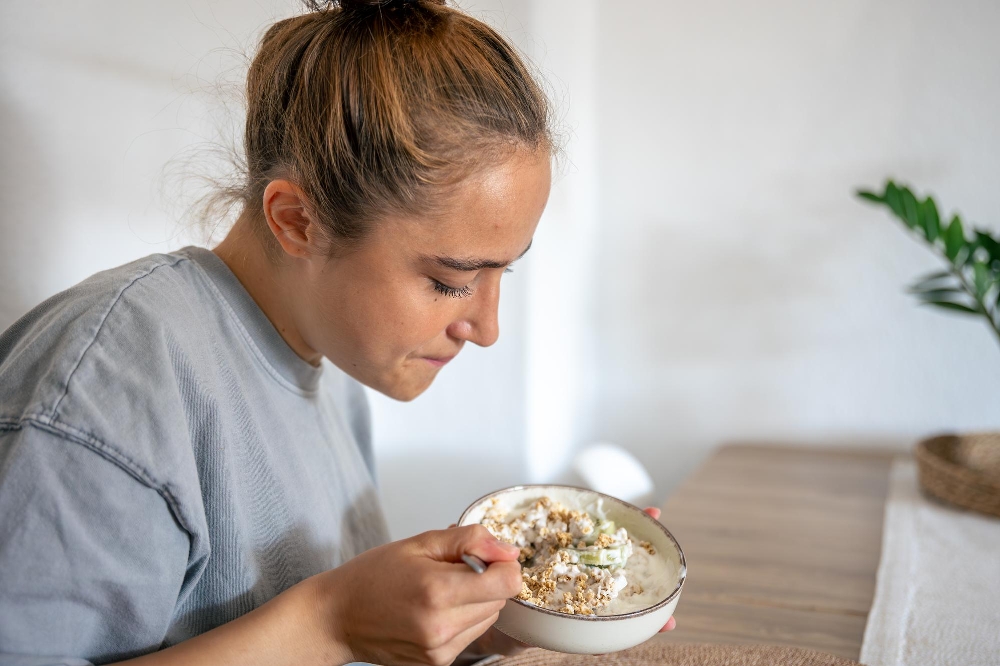 Woman with her hair in a bun looking down at a dysphagia diet bowl of food